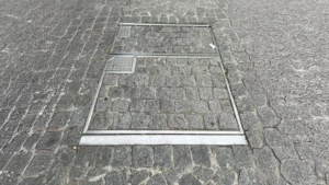 Modern kentsel alanlar ve peyzaj projeleri için peyzaj entegreli, taş dolgulu gizli metal müdahale kapağı uygulaması