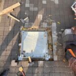 Arnavut kaldırımı taşlarıyla doldurulmuş zeminle uyumlu Steecorp metal çerçeveli, gizli taş dolgulu müdahale kapağı. Bu galvaniz kaplı kapak, peyzaj bütünlüğünü koruyan estetik bir paslanmaz rögar kapak çözümüdür.