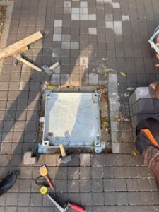 Modern kentsel alanlar ve peyzaj projeleri için peyzaj entegreli, taş dolgulu gizli metal müdahale kapağı uygulaması