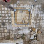 Arnavut kaldırımı taşlarıyla doldurulmuş zeminle uyumlu Steecorp metal çerçeveli, gizli taş dolgulu müdahale kapağı. Bu galvaniz kaplı kapak, peyzaj bütünlüğünü koruyan estetik bir paslanmaz rögar kapak çözümüdür.